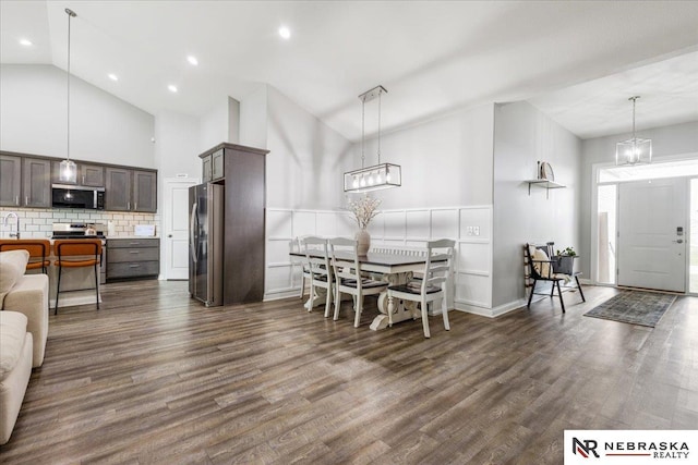 708 Sunset Blvd, Palmyra, NE 68418 - dining space featuring high vaulted ceiling, dark wood-style flooring, a chandelier, and a wainscoted wall