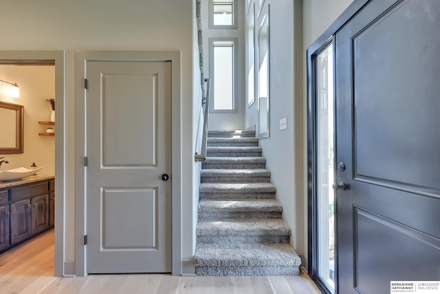 stairway with plenty of natural light and wood finished floors