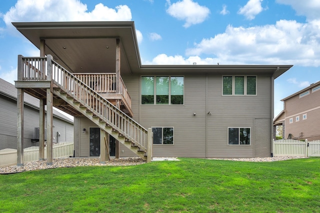 rear view of house with a lawn, fence, stairs, and a wooden deck