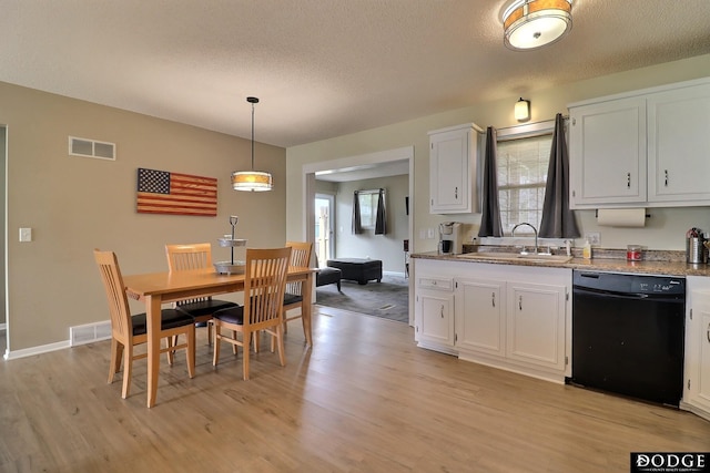 kitchen with white cabinets, black dishwasher, light wood-style flooring, and a sink