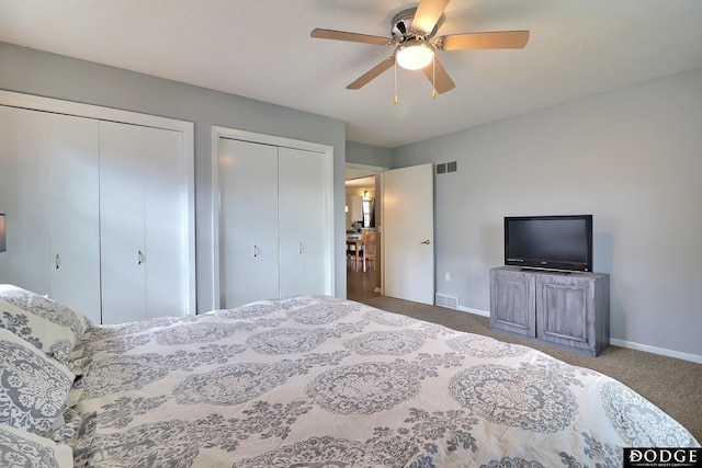 carpeted bedroom with a ceiling fan, visible vents, two closets, and baseboards