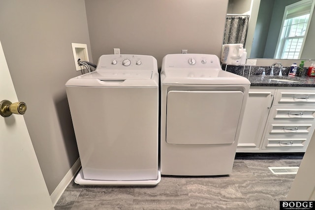 laundry room featuring wood finished floors, washing machine and clothes dryer, cabinet space, and a sink