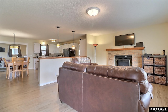living room with light wood-type flooring, a textured ceiling, and a fireplace