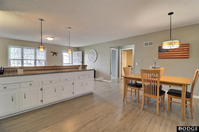 kitchen with visible vents, baseboards, white cabinetry, and light wood-style floors