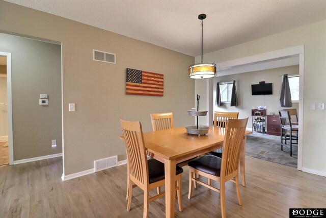 dining area featuring baseboards, visible vents, and light wood finished floors