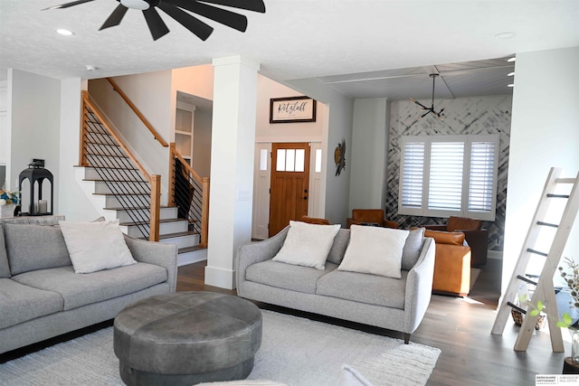 living area featuring wood finished floors, a ceiling fan, and stairs