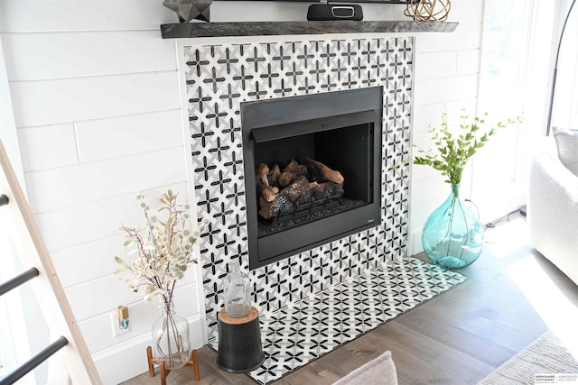 details featuring a tiled fireplace and wood finished floors