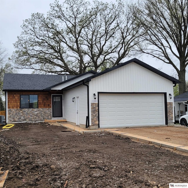 129 E 5th St, Valparaiso, NE 68065 - view of front of home with stone siding, an attached garage, driveway, and central air condition unit