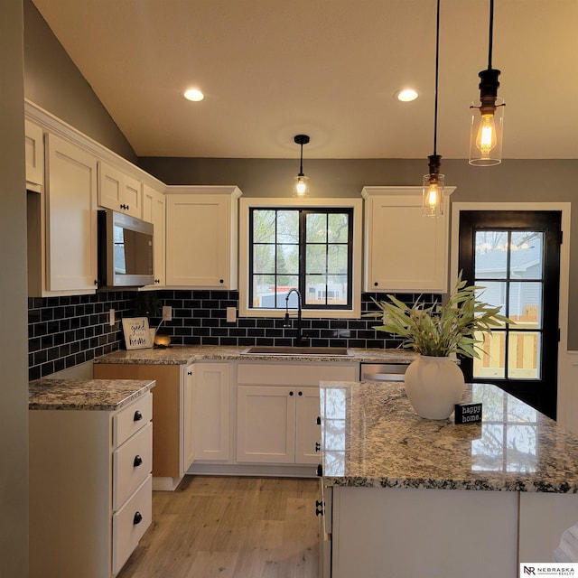 129 E 5th St, Valparaiso, NE 68065 - kitchen with stainless steel appliances, a sink, light wood finished floors, white cabinets, and light stone counters