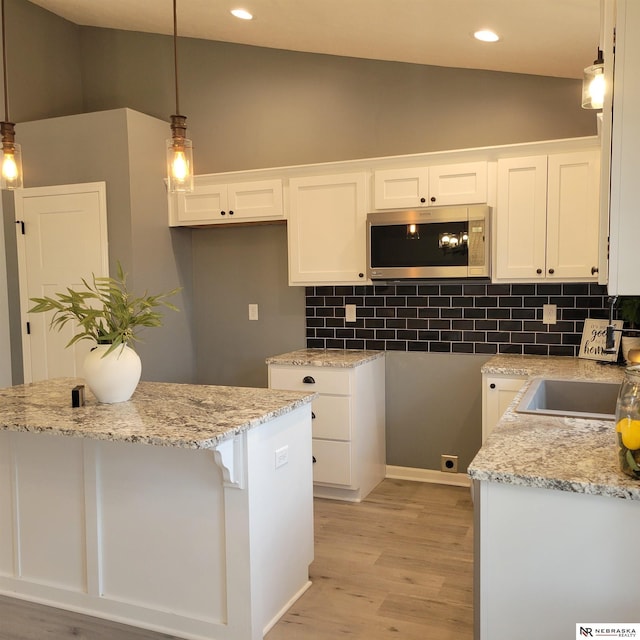 129 E 5th St, Valparaiso, NE 68065 - kitchen featuring stainless steel microwave, white cabinetry, light wood-style flooring, light stone counters, and recessed lighting