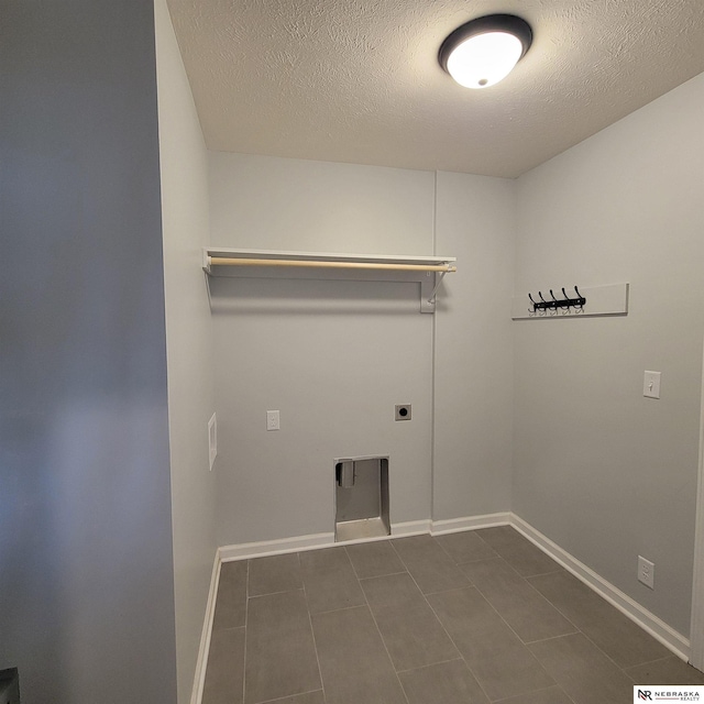 129 E 5th St, Valparaiso, NE 68065 - laundry room with hookup for an electric dryer, baseboards, a textured ceiling, and dark tile patterned floors