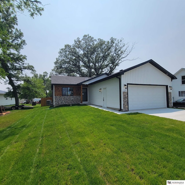 129 E 5th St, Valparaiso, NE 68065 - view of front facade featuring stone siding, an attached garage, and a front lawn