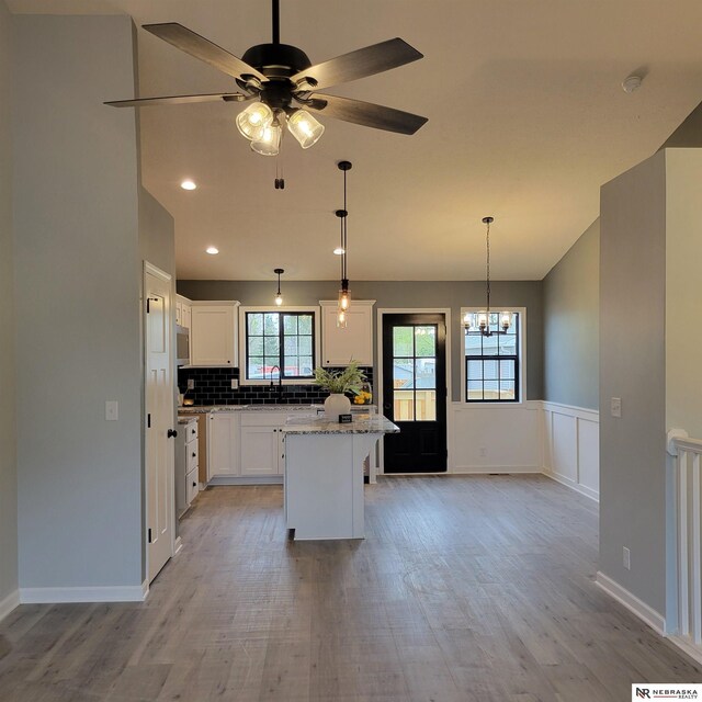 129 E 5th St, Valparaiso, NE 68065 - kitchen featuring light wood-type flooring, a center island, white cabinetry, a chandelier, and a wainscoted wall