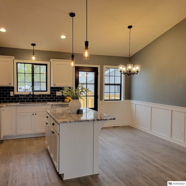 129 E 5th St, Valparaiso, NE 68065 - kitchen with a sink, light wood-style flooring, white cabinets, a kitchen island, and light stone countertops