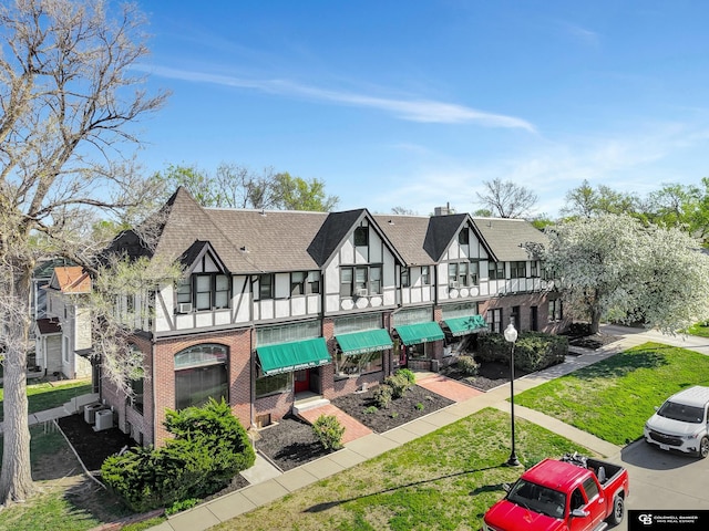 2406 J St, Lincoln, NE 68510 - exterior space featuring a shingled roof, a residential view, a lawn, central AC, and brick siding