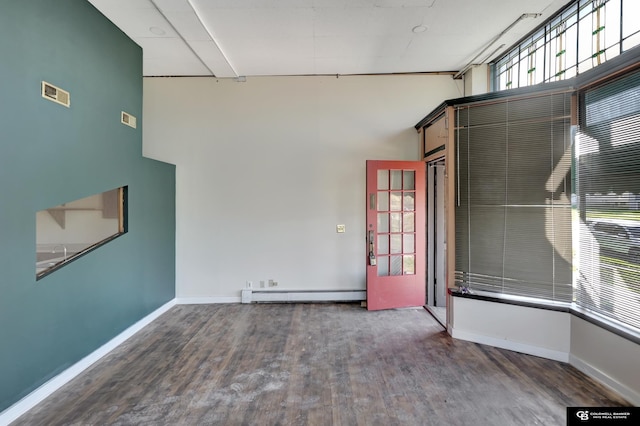 2406 J St, Lincoln, NE 68510 - empty room with wood finished floors, visible vents, a baseboard heating unit, and baseboards