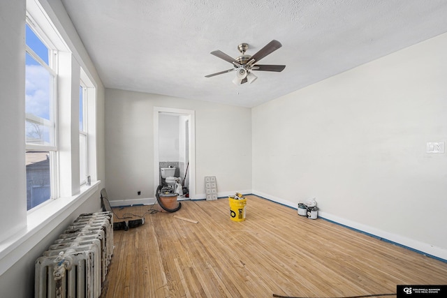 2406 J St, Lincoln, NE 68510 - unfurnished room with radiator heating unit, ceiling fan, wood finished floors, and baseboards
