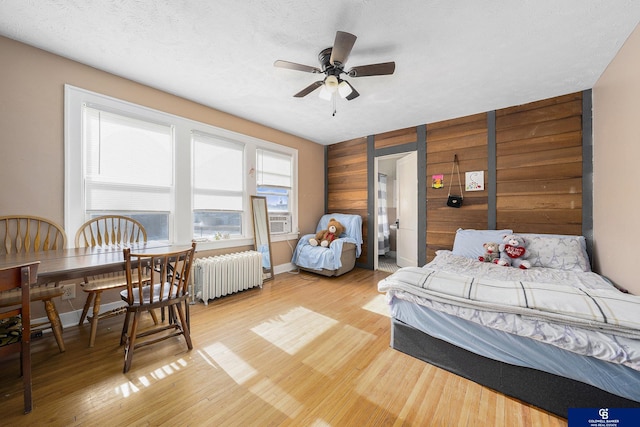 2406 J St, Lincoln, NE 68510 - bedroom with wood walls, light wood-type flooring, cooling unit, and radiator