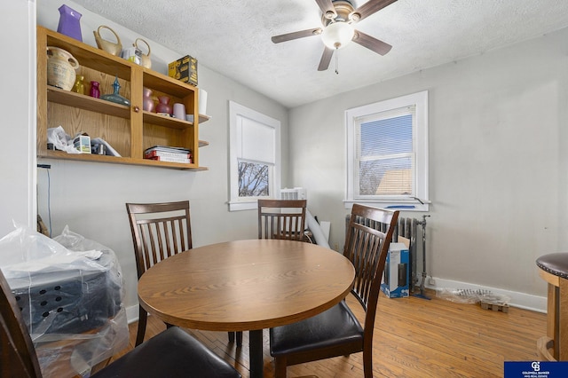 2406 J St, Lincoln, NE 68510 - dining space with wood finished floors, radiator, ceiling fan, baseboards, and a textured ceiling