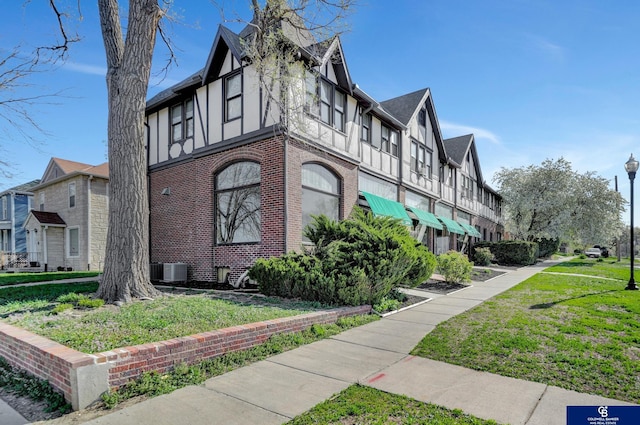 2406 J St, Lincoln, NE 68510 - view of side of home with stucco siding, brick siding, a residential view, central AC unit, and a lawn