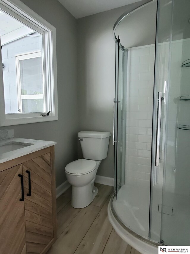 6512 Maple St, Omaha, NE 68104 - full bathroom featuring toilet, wood finished floors, a shower stall, vanity, and baseboards