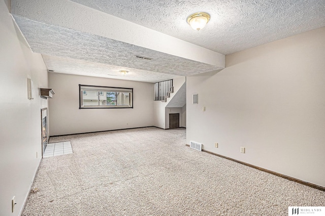 unfurnished living room featuring visible vents, stairs, carpet floors, and a textured ceiling