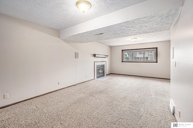 unfurnished living room featuring a textured ceiling, carpet flooring, visible vents, baseboards, and a fireplace