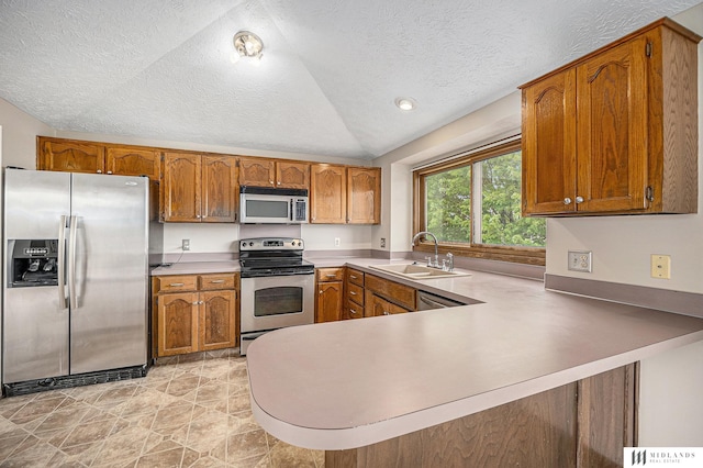 kitchen with brown cabinets, vaulted ceiling, a sink, and appliances with stainless steel finishes