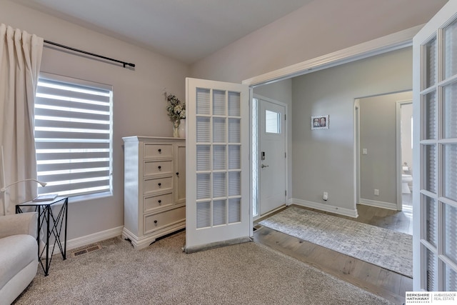 foyer entrance featuring baseboards, wood finished floors, and visible vents