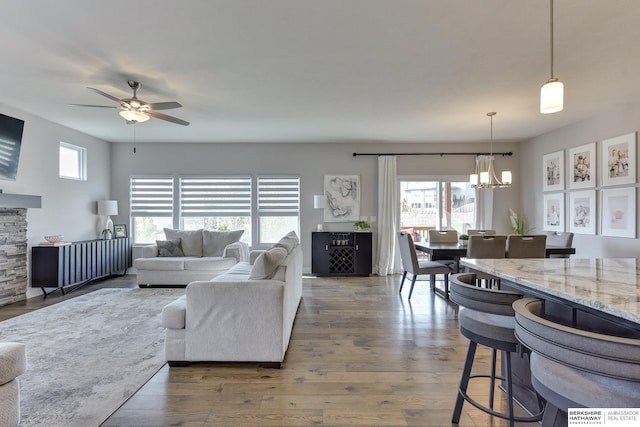 living area featuring wood finished floors and ceiling fan with notable chandelier