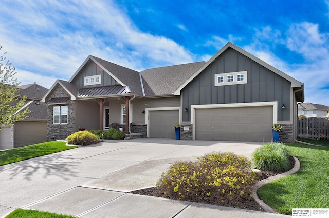 view of front facade featuring a garage, stone siding, a standing seam roof, board and batten siding, and driveway