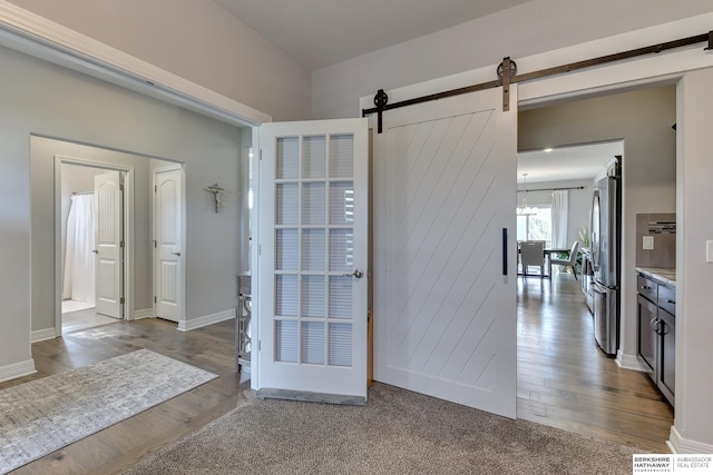 interior space with baseboards, a barn door, and wood finished floors