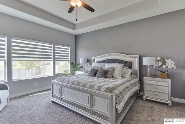 bedroom featuring baseboards, carpet flooring, a raised ceiling, and ceiling fan