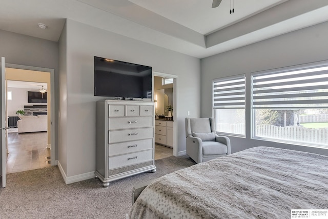 carpeted bedroom with connected bathroom and baseboards