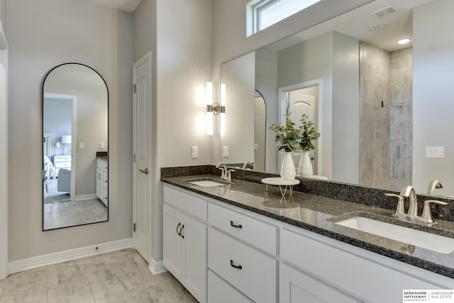 bathroom featuring a sink, baseboards, double vanity, and visible vents
