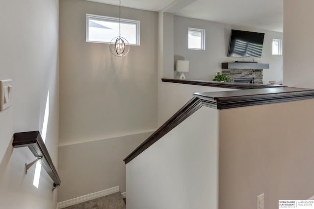stairs featuring carpet flooring, baseboards, and a stone fireplace