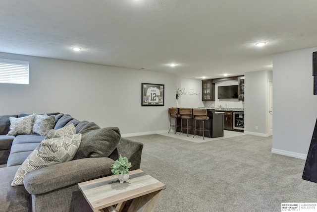 living area featuring indoor wet bar, baseboards, light carpet, and wine cooler