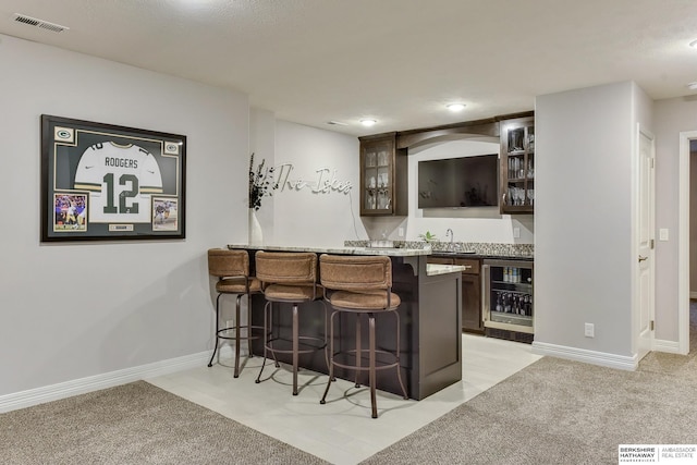 bar with visible vents, a sink, baseboards, indoor wet bar, and beverage cooler