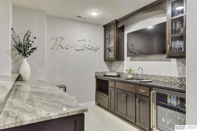 bar with visible vents, wine cooler, baseboards, a sink, and wet bar
