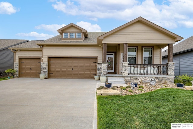craftsman-style house featuring driveway, roof with shingles, a front yard, an attached garage, and a porch
