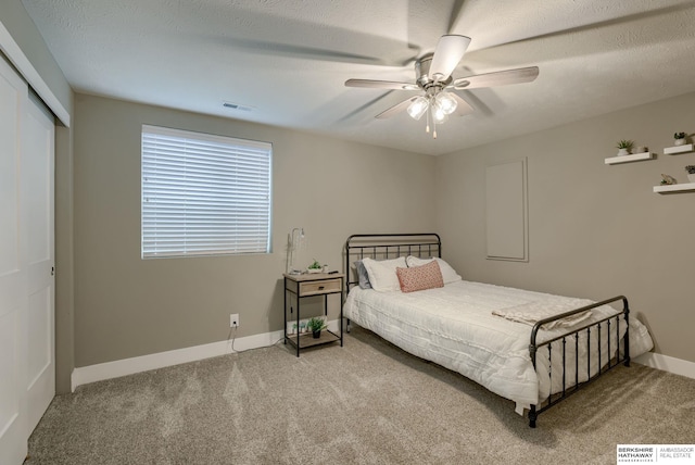 carpeted bedroom with a closet, visible vents, a ceiling fan, and baseboards