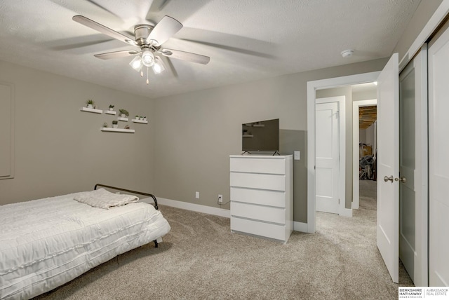 bedroom with baseboards, a ceiling fan, light carpet, and a closet