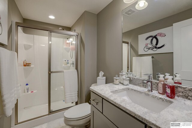 bathroom featuring visible vents, a shower stall, toilet, and vanity