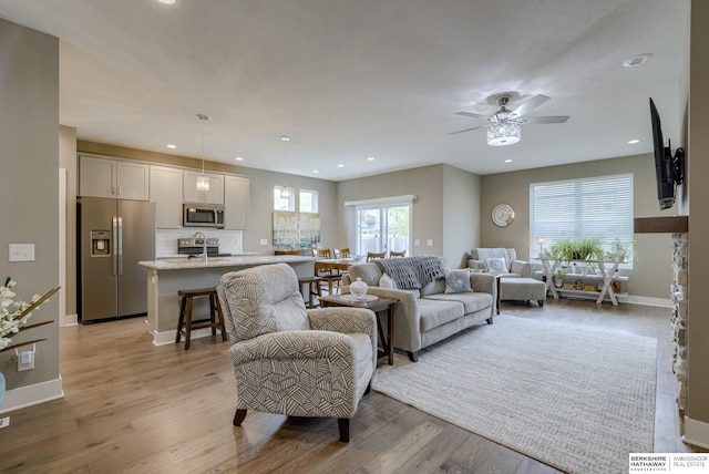 living room featuring light wood-type flooring, recessed lighting, a ceiling fan, and baseboards
