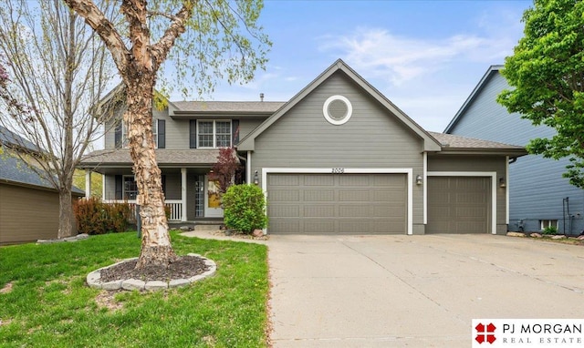 traditional-style house with covered porch, concrete driveway, a front yard, and an attached garage