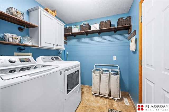 washroom with a textured ceiling, cabinet space, and washing machine and dryer