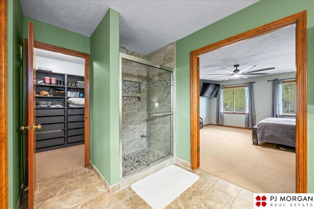 bathroom featuring a shower stall, a ceiling fan, baseboards, a textured ceiling, and ensuite bathroom