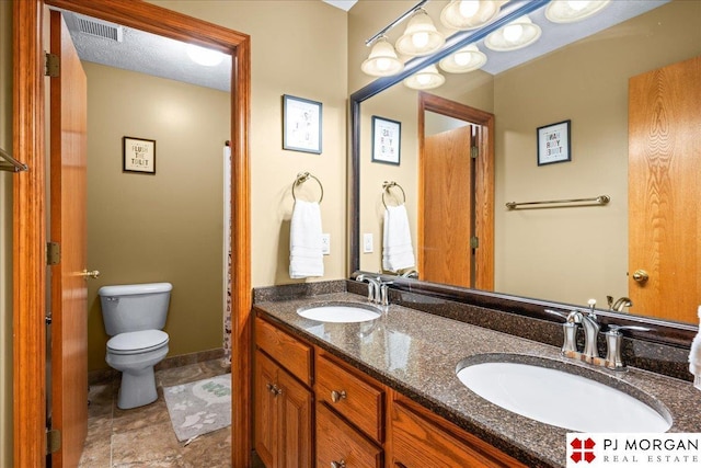 full bathroom with visible vents, toilet, double vanity, and a sink