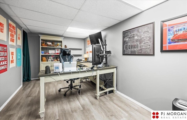 home office featuring wood finished floors, a paneled ceiling, and baseboards