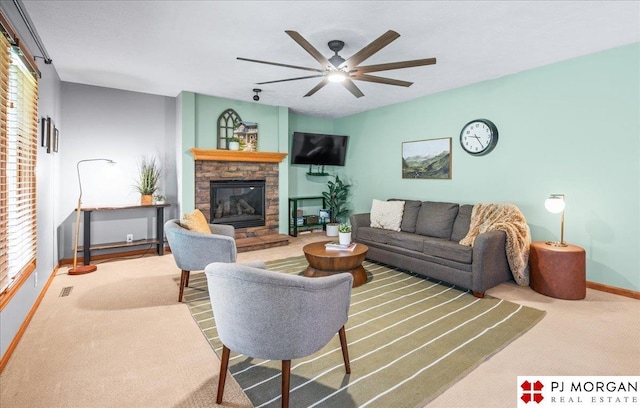 living area with visible vents, baseboards, carpet, a ceiling fan, and a stone fireplace